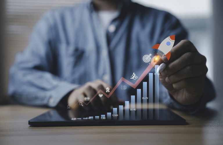 A person uses a tablet with digital graphs and icons, highlighting aspects of Business Insurance. A hand holds a rocket icon, symbolizing business growth and success as chart bars rise.