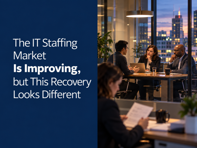 Four professionals hold a meeting in a modern office at dusk. Text beside them reads: The IT Staffing Market Is Improving, but This Recovery Looks Different, highlighting the unique challenges and opportunities shaping the current IT staffing landscape.